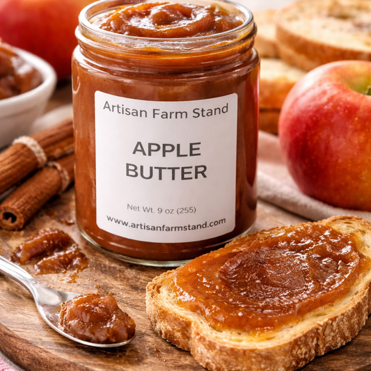 Jar of Artisan Farm Stand apple butter with a slice of toast spread with it, surrounded by apples and cinnamon sticks.