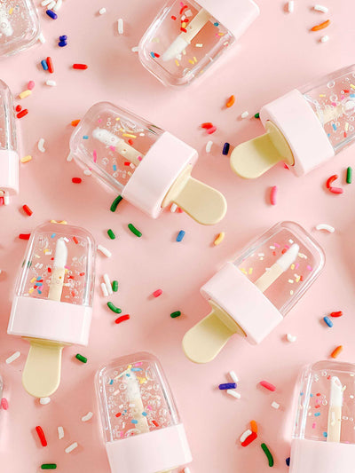 Chocolate scented lip gloss with sprinkles and nourishing ingredients, featuring a playful design.